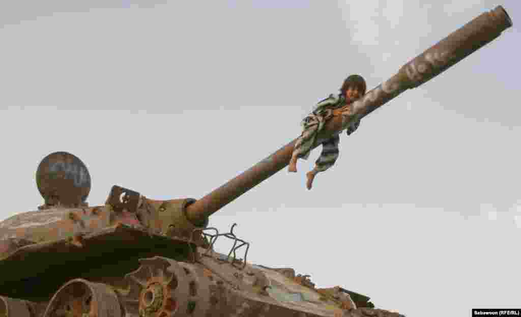 An Afghan child in Kabul climbs on the barrel of a tank on May 31, the eve of International Children&rsquo;s Day. (RFE/Sabawoon)