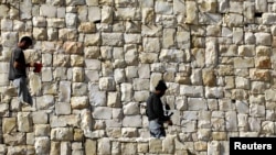 Palestinian laborers walk near houses under construction in the West Bank Jewish settlement of Beitar Ilit, near Bethlehem, on March 8.