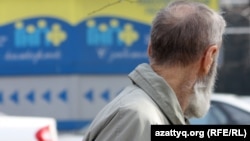 Жинақтаушы зейнетақы қорының көшедегі баннеріне қарап тұрған адам. Алматы, 29 наурыз 2012 жыл.