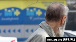 Мужчина на фоне рекламного баннера государственного накопительного пенсионного фонда в Алматы. Иллюстративное фото