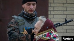 A woman walks past a Ukrainian serviceman as he stands guard in Volnovakha, Donetsk region.