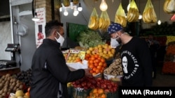 A man wearing a protective face mask and gloves buys fruits from a shop, amid fear of the coronavirus disease (COVID-19), at Tajrish Bazar in Tehran, April 2, 2020