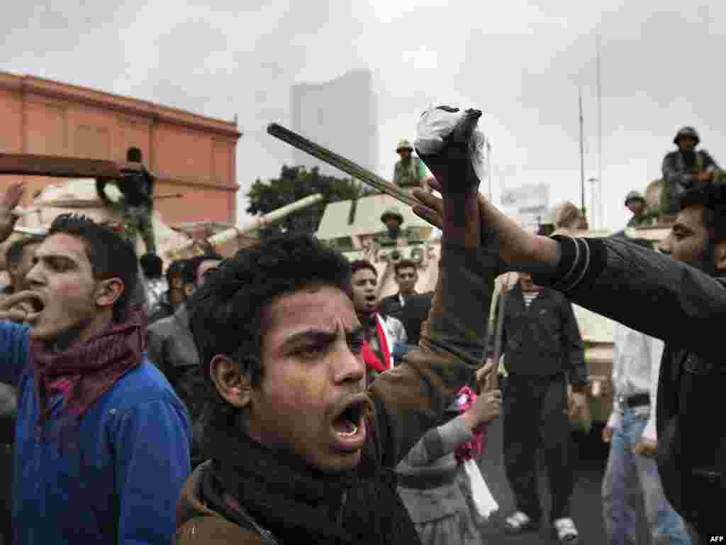 Demonstrators chant slogans in front of army tanks stationed near the National Museum in downtown Cairo on January 29.