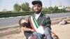 A member of Iran&#39;s Islamic Revolutionary Guards Corps (IRGC) carries an injured child.