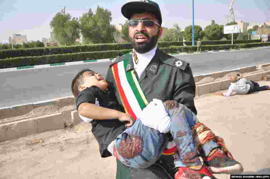 A member of Iran&#39;s Islamic Revolutionary Guards Corps (IRGC) carries an injured child.