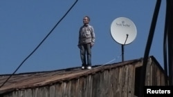 A Georgian man looks on after checking a satellite dish on the roof of a building in Tbilisi in April.
