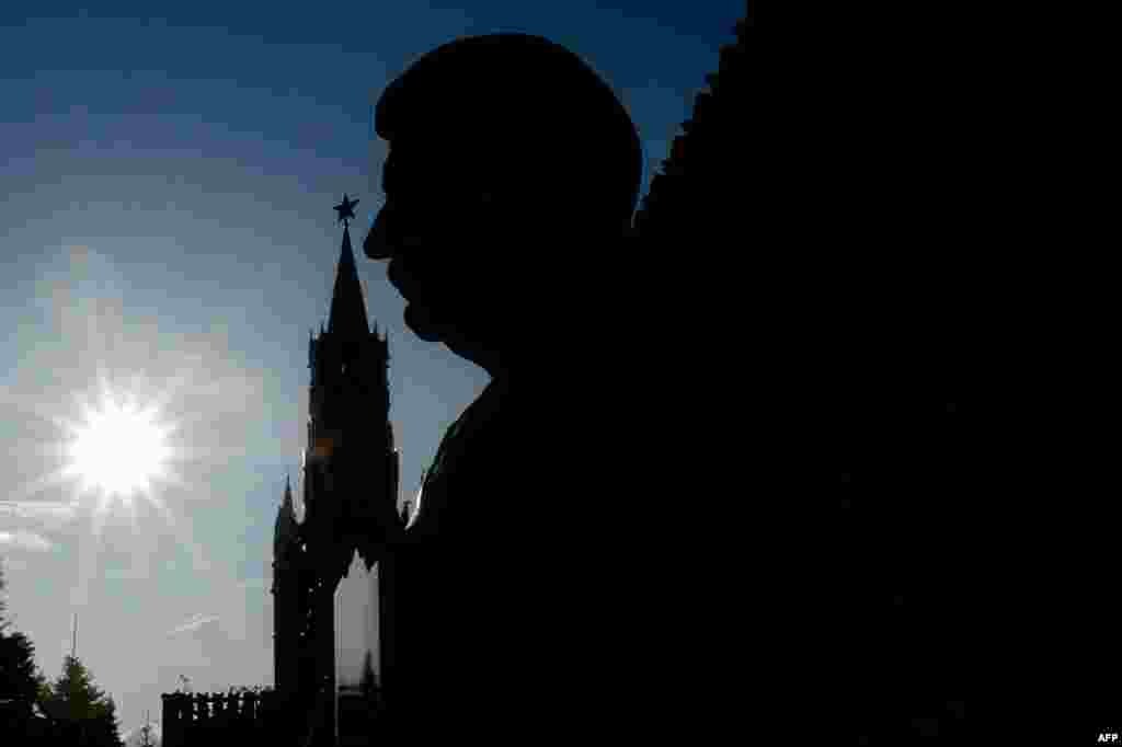 A bust of Soviet dictator Josef Stalin at his tomb and the Kremlin&#39;s Spasskaya (Saviour) Tower are silhouetted against the sky in Red Square in Moscow. (AFP/Kirill Kudryavtsev)