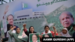 Supporters of Pakistan's ousted prime minister Nawaz Sharif hold posters of him and chant slogans as they gather at the venue where his younger brother Shahbaz Srarif will lead a rally towards the airport ahead of the arrival of Nawaz from London.