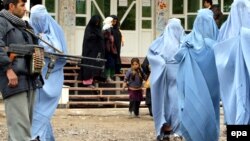 Əfqan polisi Heratda məişət zorakılığı mövzusunda seminardan çıxan burkalı qadınları qoruyur. 2009-cu il.