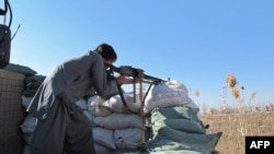 An Afghan police officer keeps watch during an ongoing battle with Taliban militants in Helmand Province in December 2015.