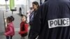 A Roma family walks past a police officer as they arrive at the Lille-Lesquin airport, near Lille in northern France, for their flight to Romania on September 16.