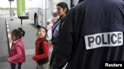 A Roma family walks past a police officer as they arrive at the Lille-Lesquin airport, near Lille in northern France, for their flight to Romania on September 16.