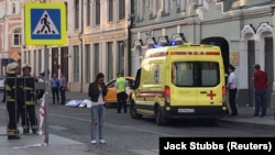 An ambulance is parked near a damaged taxi, which ran into crowds of people in Moscow on June 16.