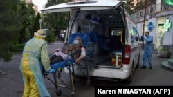 Armenia - An ambulance rescuer wearing personal protective equipment moves a patient into the Grigor Lusavorich Medical Centre in Yerevan on May 27, 2020, amid the COVID-19 pandemic.