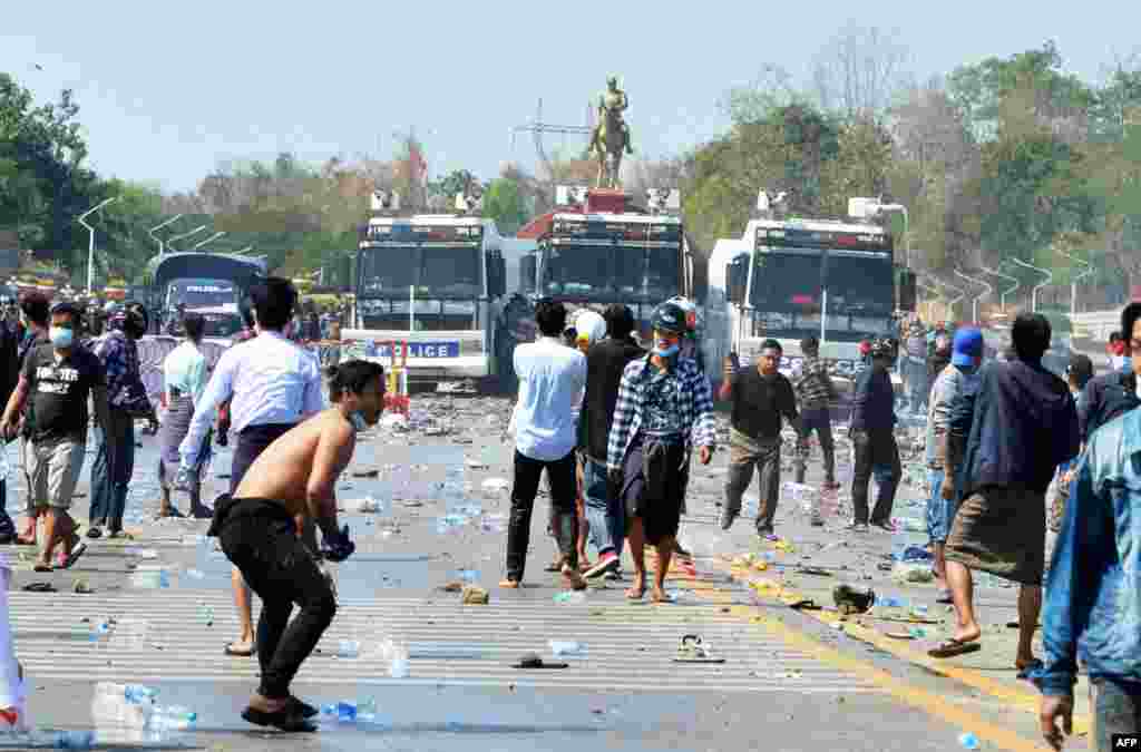 Protesters confront police vehicles after firing water cannons during a demonstration against the February 1 military coup at the monument of General Aung San (C), the late father of detained Myanmar leader Aung San Suu Kyi in the capital Naypyidaw on February 9, 2021. (Photo by STR / AFP)