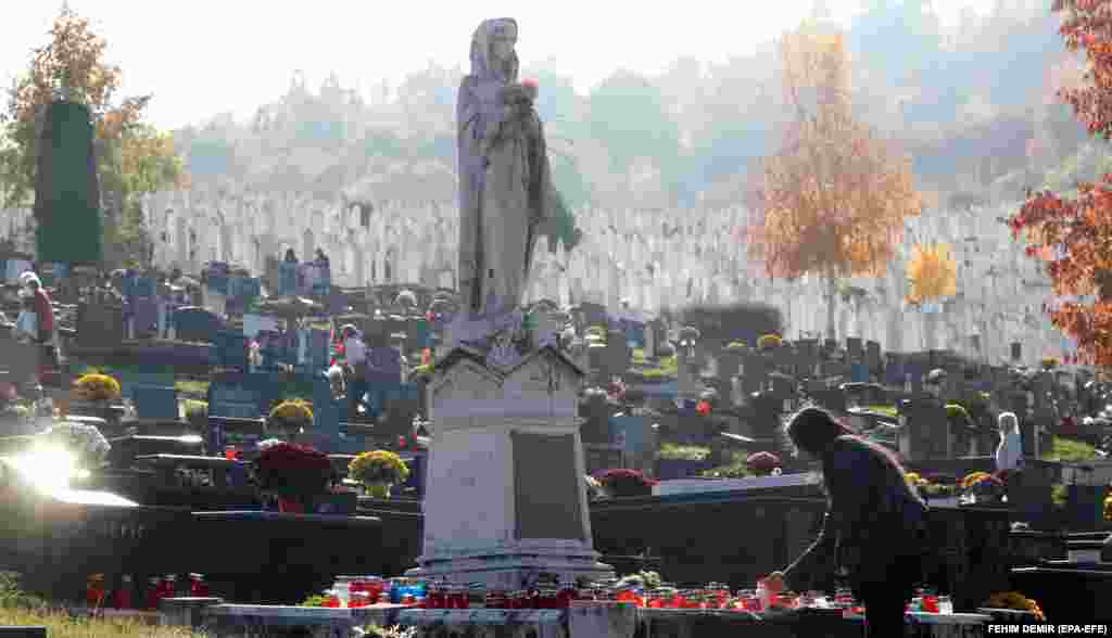 A Catholic Bosnian woman lights a candle at a grave in Bare cemetery in Sarajevo on November 1.