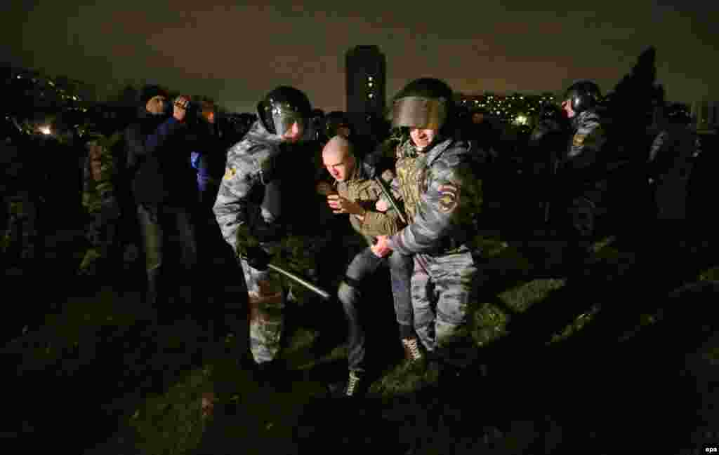 Во время разрушительных массовых протестов, вызванных сообщениями о том, что трудовой мигрант убил местного русского жителя, полицейские задержали одного из протестующих националистов в Москве в октябре 2013 года. 