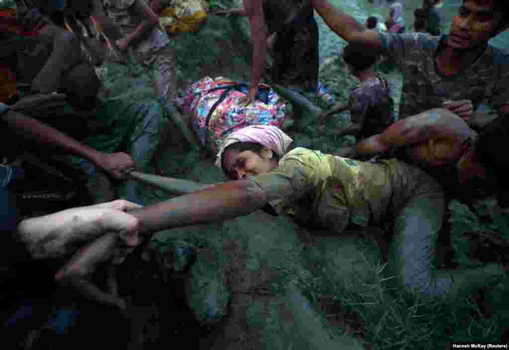 Photographers help a Rohingya refugee out of a river as she flees from Myanmar to Bangladesh, November 1, 2017. (Reuters/Hannah McKay) 