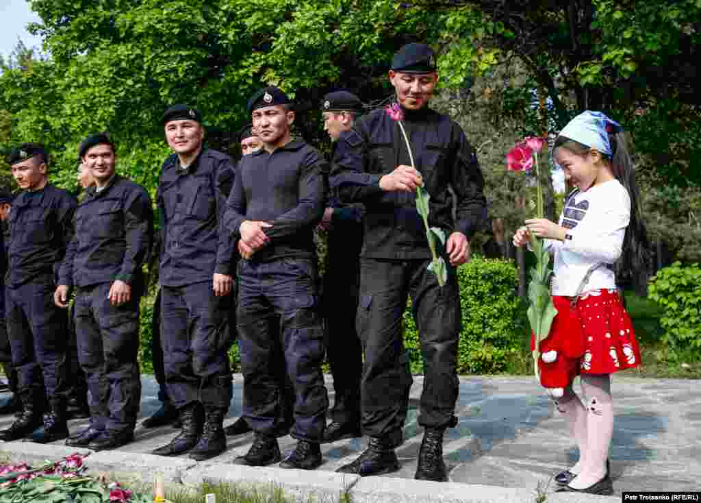 Девушка дарит цветок сотруднику полиции во время акции протеста в Алматы в День единства народа Казахстана в Алматы 1 мая. (Pyotr Trotsenko, RFE/RL)