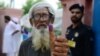 An elderly Pakistani man shows his inked thump outside a polling station after casting his vote in national elections in Lahore on July 25. 