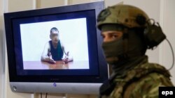 Сотрудник службы безопасности Украины на пресс-конференции стоит рядом с экраном, на котором демонстрируется видеозапись с допросом Владимира Старкова, Киев, 29 июля 2015.