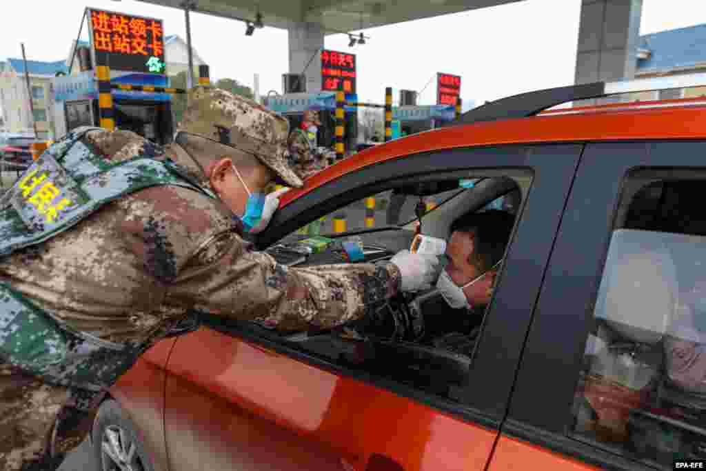 Милиция проводит проверку температуры на выезде на платное шоссе из Уханя без защитных костюмов, 23 января 2020 года