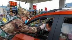 Сотрудник полиции проверяет температуру у водителя в Ухане. Китай, 23 января 2020 года.