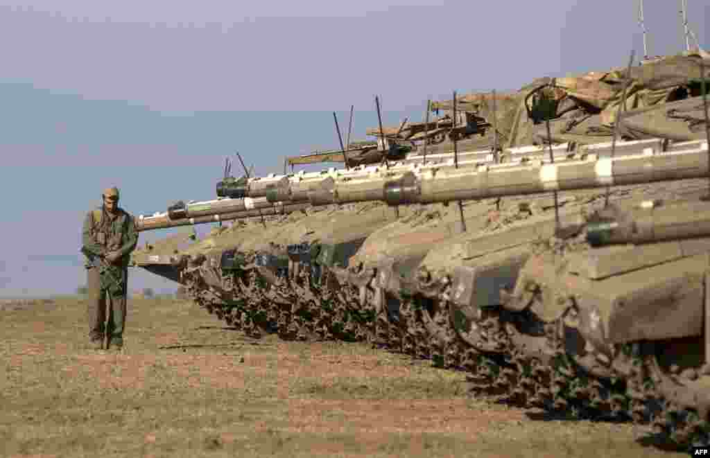 An Israeli soldier walks next to Merkava tanks stationed in a deployment training area in the Israeli-annexed Golan Heights near the border with Syria. Israel will strike back &quot;fiercely&quot; if Syria attacks the Jewish state, Prime Minister Benjamin Netanyahu has said, as the U.S. mulls military action against the Syrian regime. (AFP/Menahem Kahana)