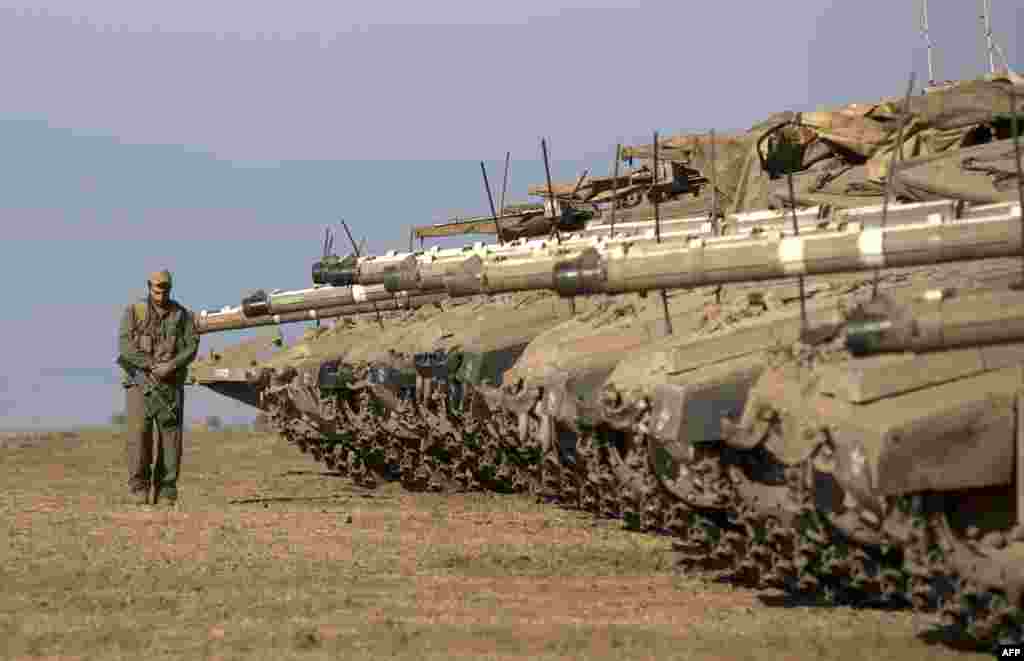 An Israeli soldier walks next to Merkava tanks stationed in a deployment training area in the Israeli-annexed Golan Heights near the border with Syria. Israel will strike back "fiercely" if Syria attacks the Jewish state, Prime Minister Benjamin Netanyahu has said, as the U.S. mulls military action against the Syrian regime. (AFP/Menahem Kahana)