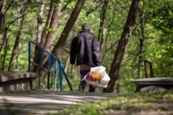 Безхатченко з пакетами прямує з території «Павлівської» лікарні у Кирилівській гай