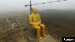 China -- A crane is seen next to a giant statue of Chinese late chairman Mao Zedong under construction near crop fields in a village of Tongxu county, Henan province, January 4, 2016