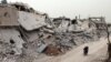 Syrians ride a motorcycle amid the destruction in a neighborhood in the rebel-held area of Daraa in April.