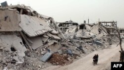 Syrians ride a motorcycle amid the destruction in a rebel-held neighborhood in Daraa, April 12, 2017