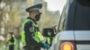 Сотрудник Патрульной милиции проверяет документы у водителя автомобиля во время действия режима ЧП. 31 марта 2020 года.