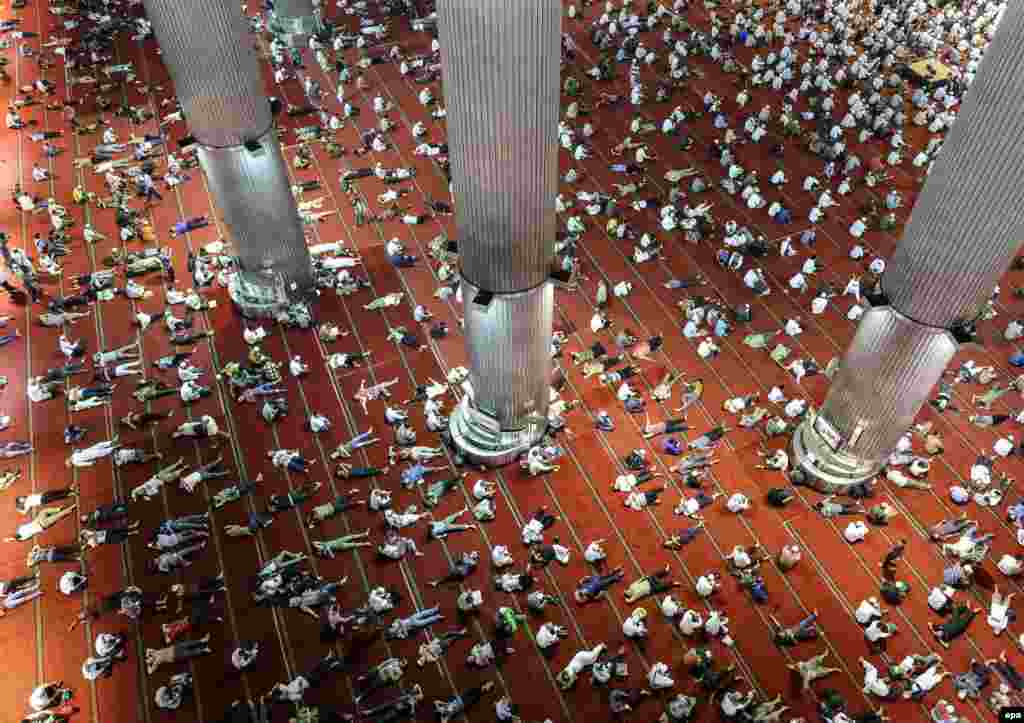 Indonesian Muslims lay down on the floor as others read the Koran shortly after Friday Prayers in a Jakarta mosque on June 9. (epa/Mast Irham)