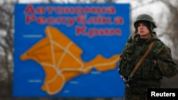 Российский солдат стоит перед картой Крыма. Керчь, 4 марта 2014 года.
