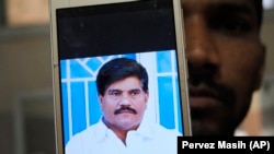 An employee of a local television channel shows a picture of slain journalist Aziz Memon on his mobile, after a demonstration to condemn his killing, in Hyderabad on February 17,