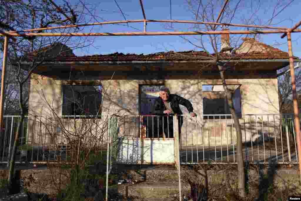 Knezevic poses in front of his damaged house in Knin.