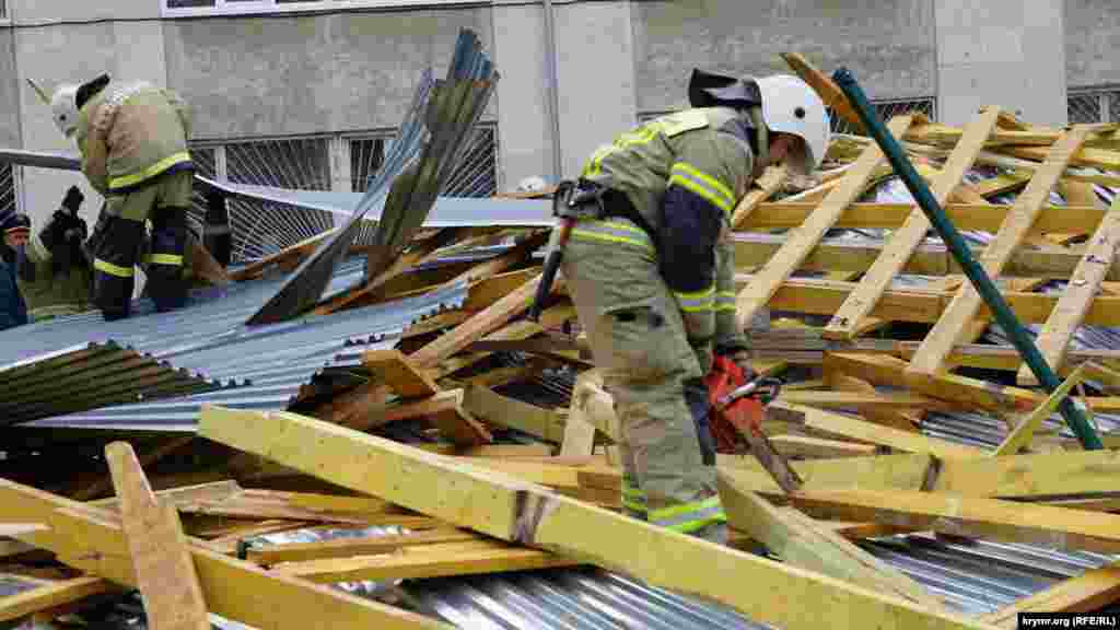 Спасатели разрезают сорванные деревянные стропила и обрешетку