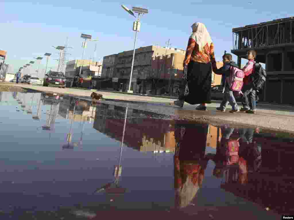 یک روز پس از انفجار بمب در ناحیه شوله در بغداد- ۱۲ آبان - Residents are reflected in a pool of blood a day after a bomb attack struck Shula district in Baghdad November 3, 2010. The death toll from a series of bomb blasts in mainly Shi'ite areas of Baghdad on Tuesday evening reached 64, while 360 people were wounded, Iraq's health minister said on Wednesday. REUTERS/Saad Shalash (IRAQ - Tags: CONFLICT POLITICS CIVIL UNREST) POTW44