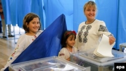 Жінка зі своїми дітьми на виборчій дільниці. Київ, 25 травня 2014 року