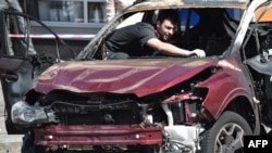 A Ukrainian police officer examines the charred automobile of journalist Pavel Sheremet after he was killed by a car bomb in Kyiv on July 20.