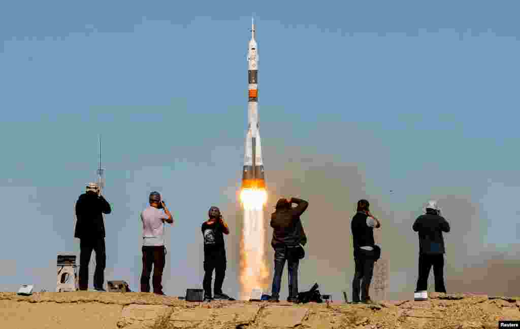 Photographers take pictures as the Soyuz MS-10 spacecraft blasts off.