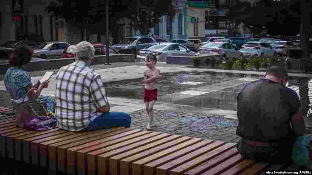 Девочка спасается от жары в одном из фонтанов Симферополя