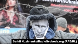 A protester holds up a mask of Russian President Vladimir Putin during a rally against Russian aggression in Kyіv. Freedom House says Moscow further reduced the space for public dissent and political opposition at home in 2016.