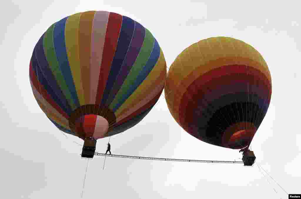 Aisikaier Wubulikasimu, a 40-year-old Uyghur acrobat, walks on an 18-meter-long tightrope strung between two hot air balloons in Shilin county, in China's Yunnan Province. (Reuters/Stringer)