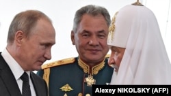 Președintele rus Vladimir Putin (stânga), patriarhul Kirill al Moscovei (dreapta) și ministrul Apărării, Sergei Shoigu