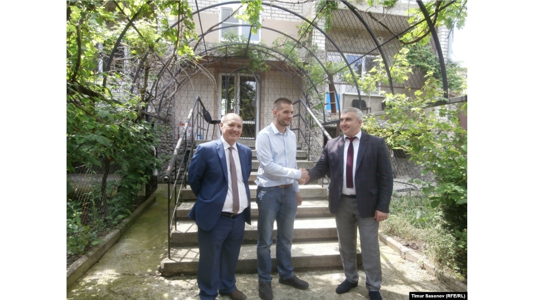 Poluboyarenko (left), Martens (center), and Abazov stand in front of the house that Poluboyarenko offered to the Martenses.