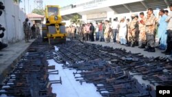 Pakistani paramilitary soldiers watch as a steamroller destroys weapons seized during various search operations against criminal gangs and banned organizations in Karachi on January 6.