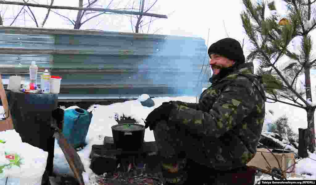 Військовий на блок-посту гріється біля багаття. Він з радістю зустрічає волонтерів з Волновахи.